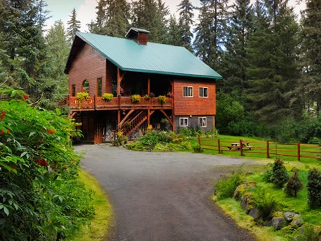 Carriage House Lodge and Cottages — Carriage House’s timber lodge among trees in Girdwood