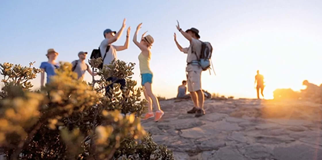 Cape Town — friends celebrating a mountaintop view in warm evening light